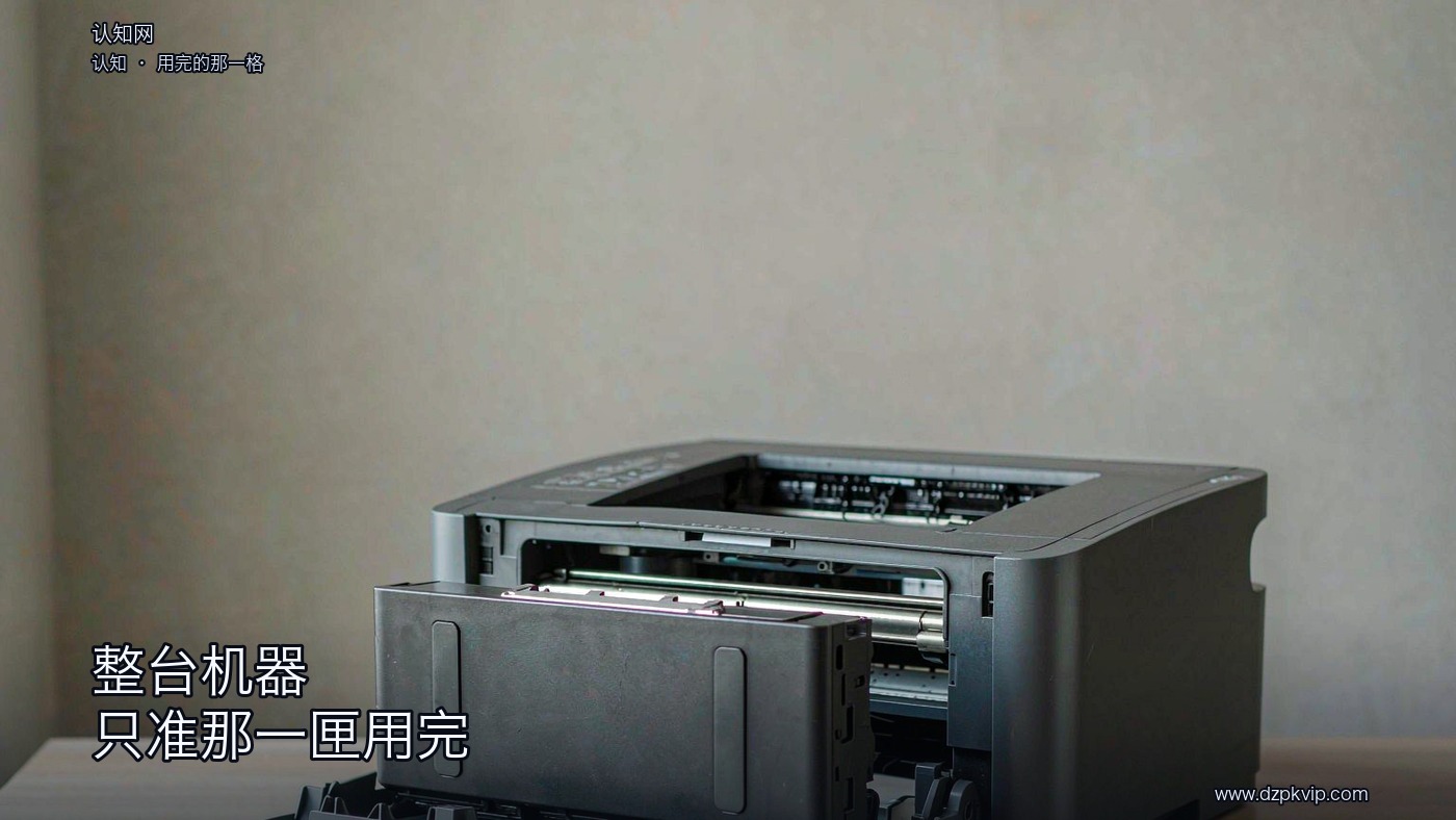 一台深灰色的办公打印设备,前盖敞开着,一只方形的替换件从机身里抽出了一半,露出机内两段平行的金属轨道;设备摆在浅木色的台面上,背后是一面素净的浅灰墙,一道柔和的天光从左上照来;画面里没有人物,也没有任何文字